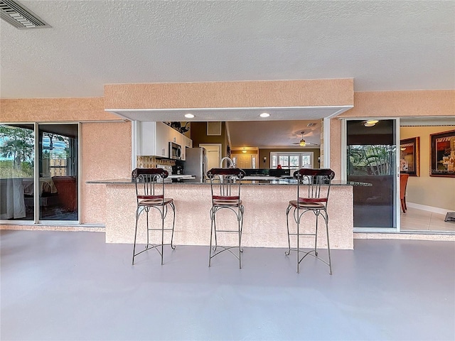 kitchen featuring a kitchen bar, visible vents, concrete floors, and appliances with stainless steel finishes