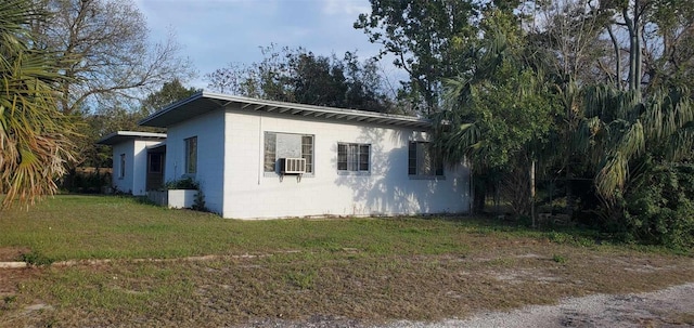 view of side of home with concrete block siding and a lawn