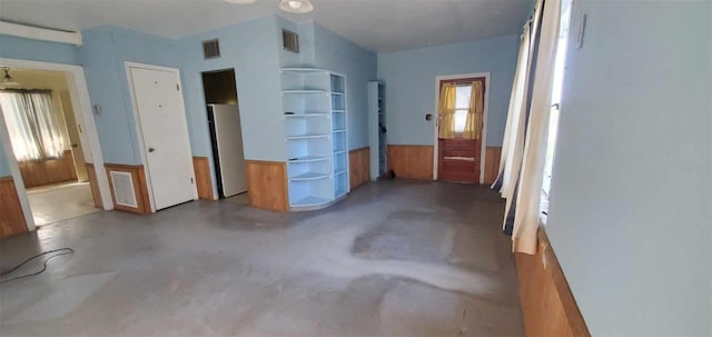 unfurnished bedroom featuring visible vents, concrete flooring, and refrigerator