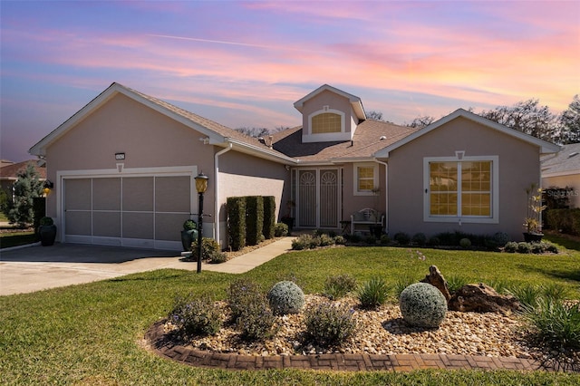 view of front of property featuring a garage, a yard, concrete driveway, and stucco siding