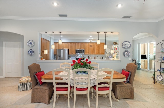 dining room with light tile patterned floors, visible vents, arched walkways, and ornamental molding