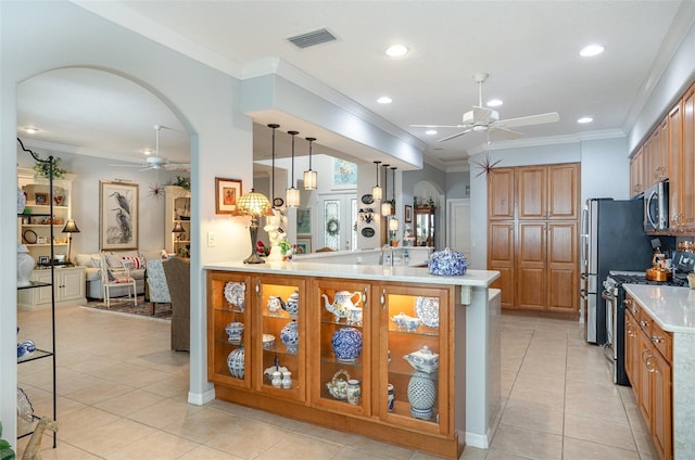 kitchen featuring brown cabinetry, appliances with stainless steel finishes, arched walkways, and light countertops