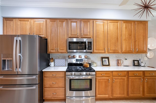 kitchen with brown cabinets, stainless steel appliances, decorative backsplash, and light countertops