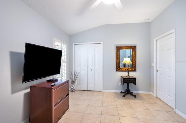 bedroom featuring lofted ceiling, a closet, ceiling fan, and light tile patterned floors