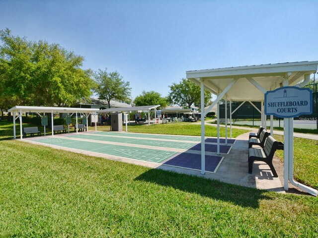 view of property's community featuring shuffleboard and a yard