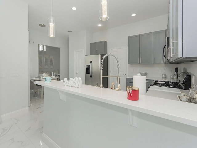 kitchen with gray cabinetry, a peninsula, a kitchen breakfast bar, marble finish floor, and light countertops