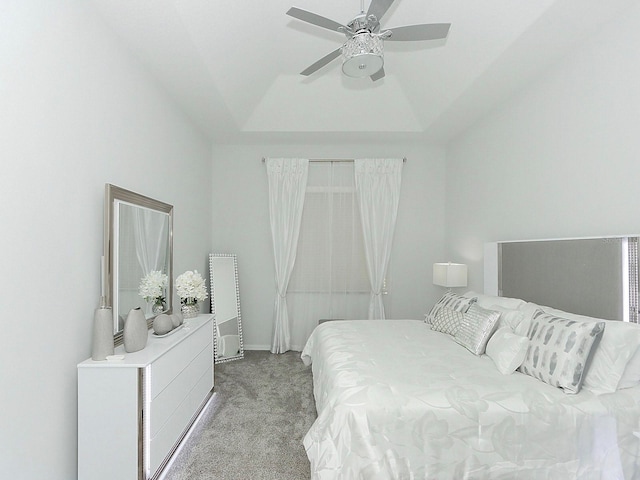 bedroom with a raised ceiling, light colored carpet, and ceiling fan