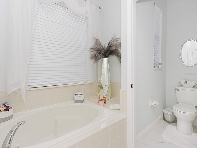 bathroom featuring baseboards, toilet, and a bath