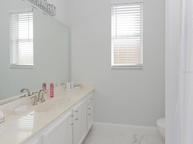 bathroom with toilet, marble finish floor, vanity, and baseboards