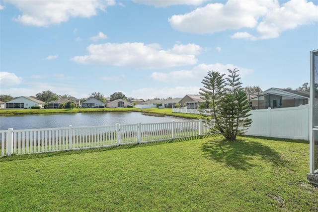 view of yard featuring a water view, a fenced backyard, and a residential view