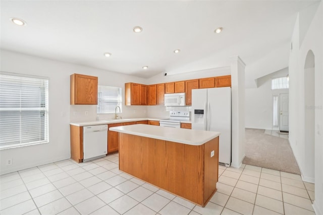 kitchen with light tile patterned floors, lofted ceiling, white appliances, light countertops, and a center island