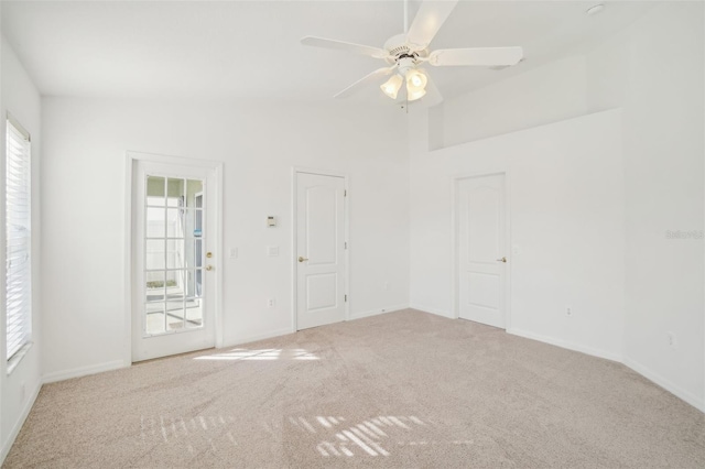 carpeted spare room featuring vaulted ceiling, a ceiling fan, and baseboards