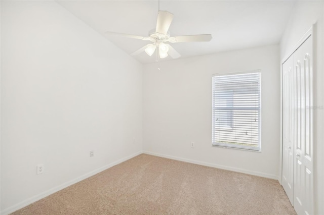 empty room featuring a ceiling fan, light carpet, and baseboards