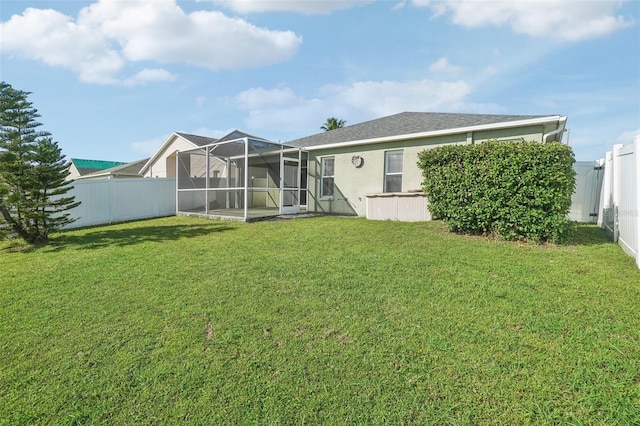 back of property with a yard, a fenced backyard, glass enclosure, and stucco siding