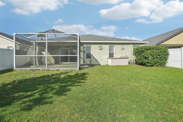 back of property featuring a patio, a lanai, fence, a yard, and stucco siding