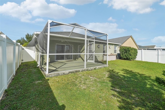 rear view of property with a lanai, a patio area, a fenced backyard, and a lawn