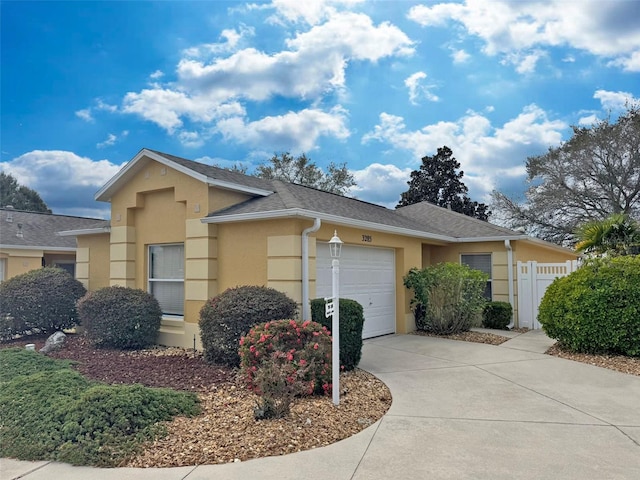 ranch-style home featuring an attached garage, roof with shingles, concrete driveway, and stucco siding