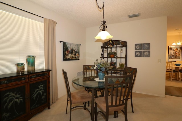 dining space featuring light colored carpet, a notable chandelier, and a textured ceiling