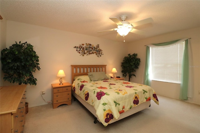 bedroom with a textured ceiling, a ceiling fan, and light colored carpet