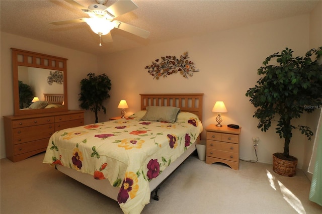 bedroom featuring a ceiling fan, a textured ceiling, and light colored carpet