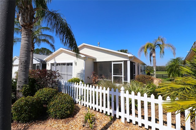 view of front of property with a fenced front yard, a sunroom, and an attached garage