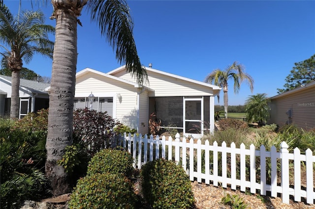 view of property exterior with a sunroom and fence