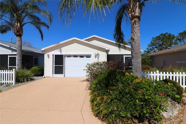 view of front facade with driveway, an attached garage, and fence