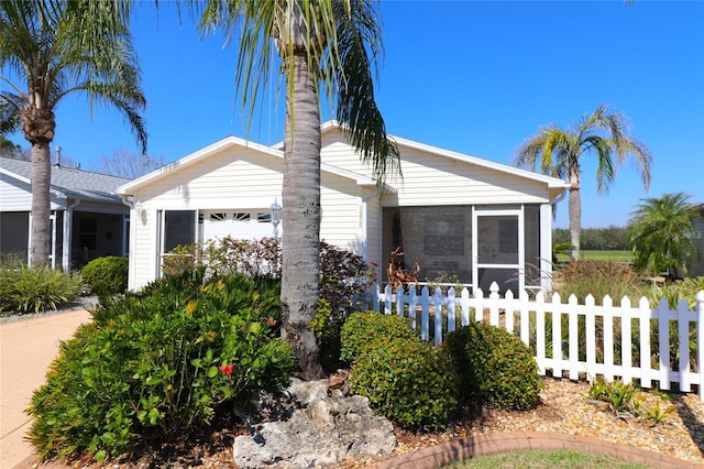 view of property exterior with a garage, a sunroom, and fence