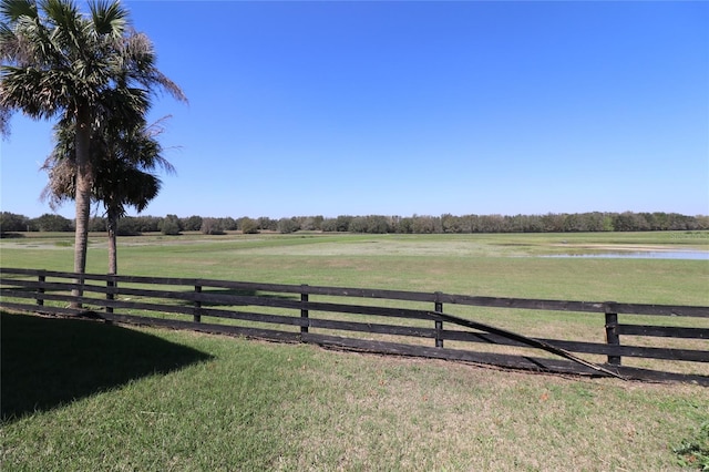 view of yard featuring a rural view, a water view, and fence