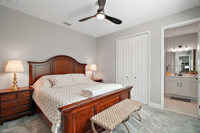 bedroom featuring a closet, light colored carpet, visible vents, a ceiling fan, and connected bathroom