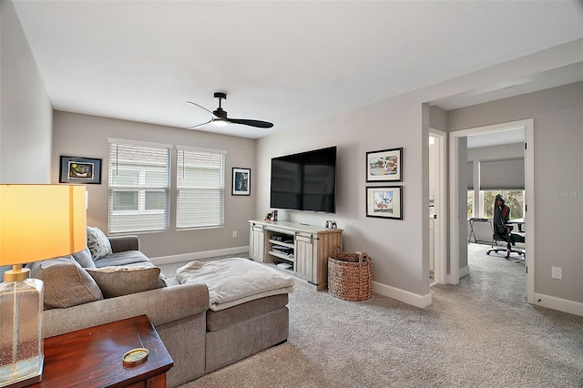 living room with light colored carpet, ceiling fan, and baseboards