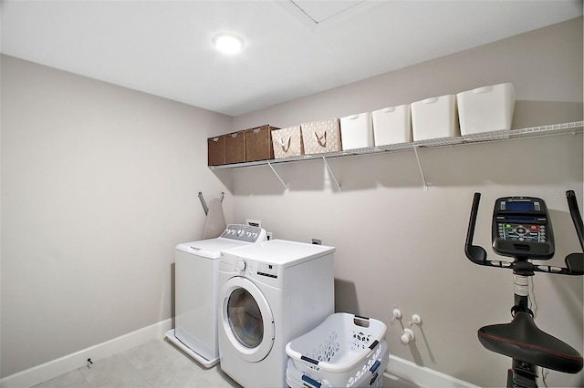 clothes washing area featuring light tile patterned floors, laundry area, separate washer and dryer, and baseboards