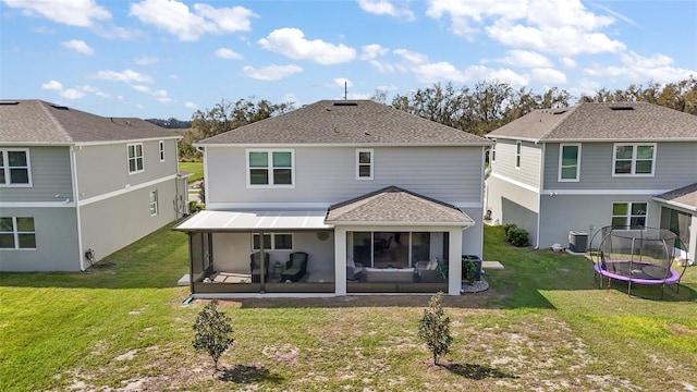 back of property featuring a lawn, a sunroom, roof with shingles, a trampoline, and central AC