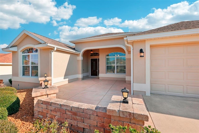 view of front of home with a garage, roof with shingles, and stucco siding