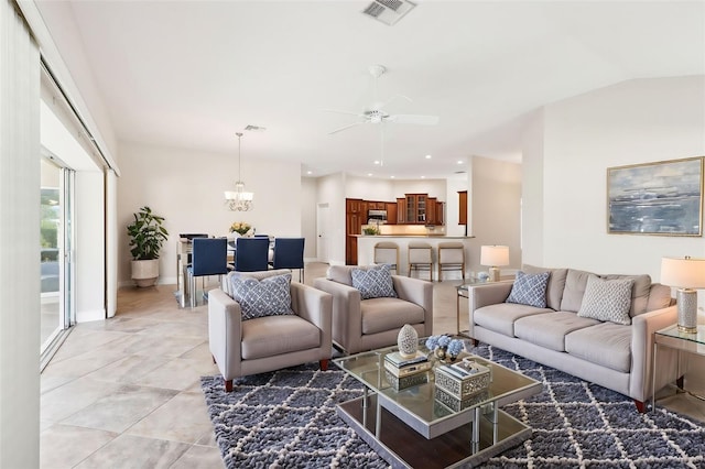 living area with light tile patterned floors, baseboards, visible vents, lofted ceiling, and ceiling fan with notable chandelier