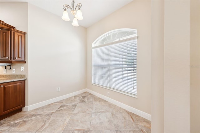 unfurnished dining area with lofted ceiling, baseboards, and a notable chandelier