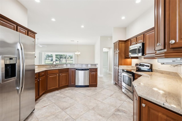 kitchen with light stone counters, recessed lighting, appliances with stainless steel finishes, a sink, and a peninsula