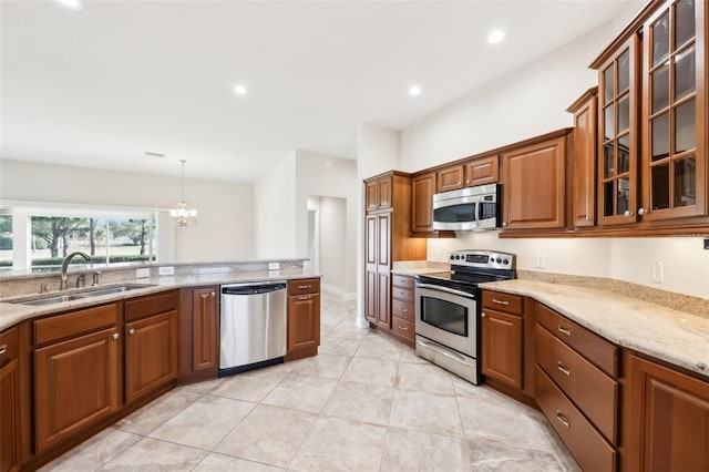 kitchen with recessed lighting, stainless steel appliances, a sink, brown cabinets, and light stone countertops