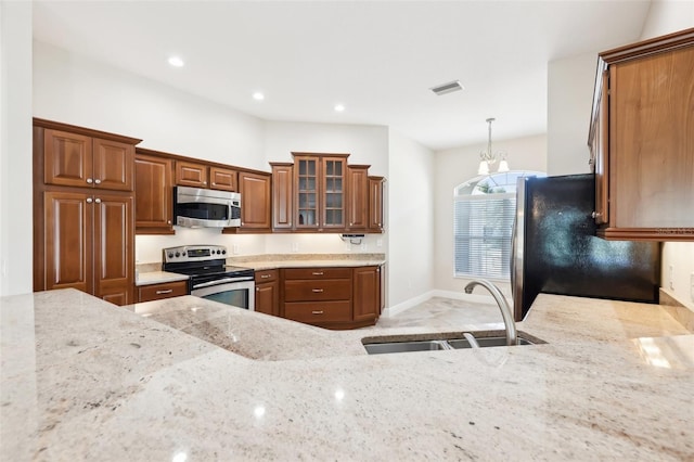 kitchen with brown cabinets, visible vents, appliances with stainless steel finishes, a sink, and light stone countertops