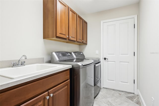 washroom with light tile patterned floors, washing machine and dryer, a sink, baseboards, and cabinet space