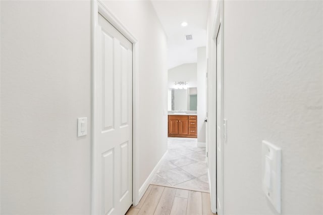 hallway with recessed lighting, visible vents, a sink, light wood-type flooring, and baseboards