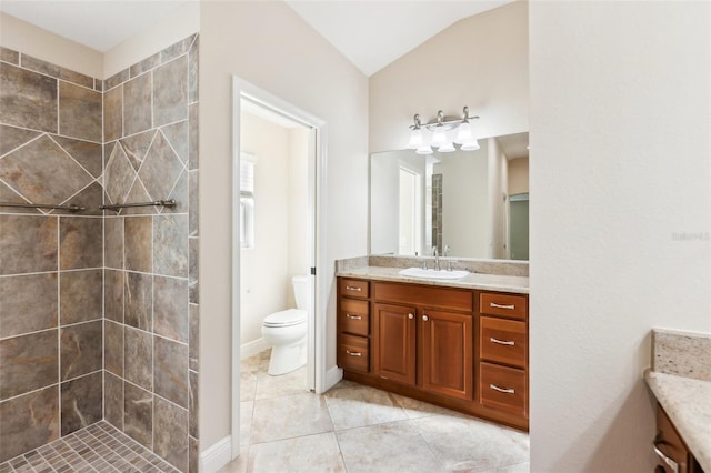 bathroom featuring toilet, tile patterned floors, vaulted ceiling, a tile shower, and vanity