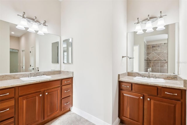 full bath with baseboards, two vanities, a sink, and tiled shower