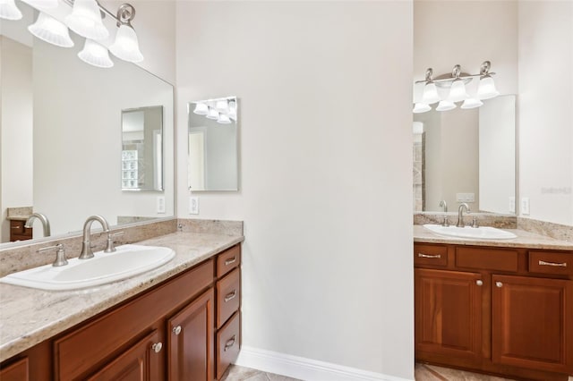 full bath with two vanities, a sink, and baseboards