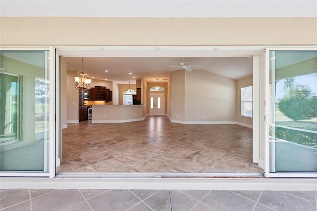 interior space featuring baseboards, lofted ceiling, open floor plan, pendant lighting, and ceiling fan with notable chandelier