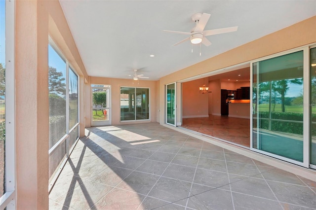 unfurnished sunroom featuring ceiling fan with notable chandelier