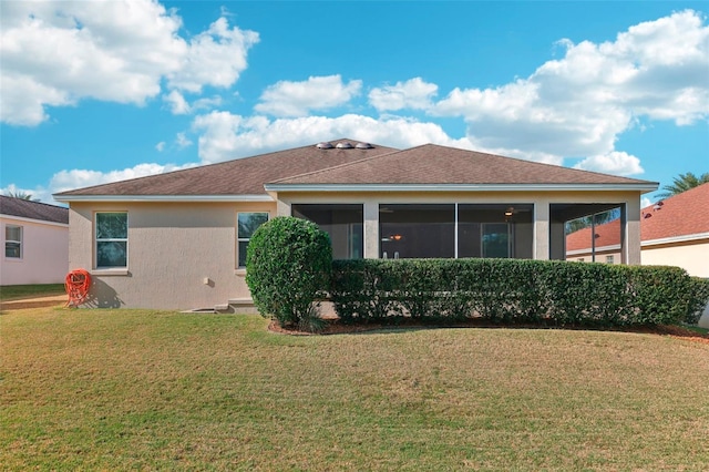 rear view of property featuring a yard, a sunroom, and stucco siding