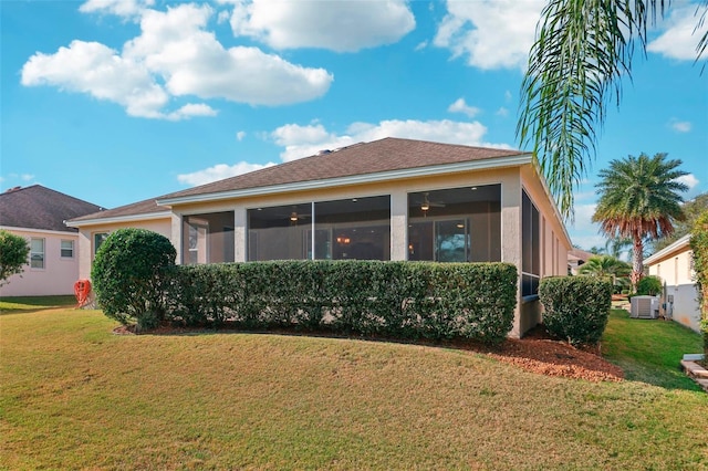 rear view of property featuring a sunroom, a lawn, central AC unit, and stucco siding