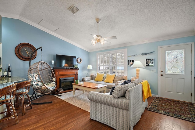 living area with lofted ceiling, visible vents, wood finished floors, and ornamental molding