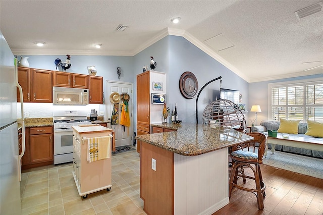 kitchen featuring ornamental molding, lofted ceiling, white appliances, and a center island